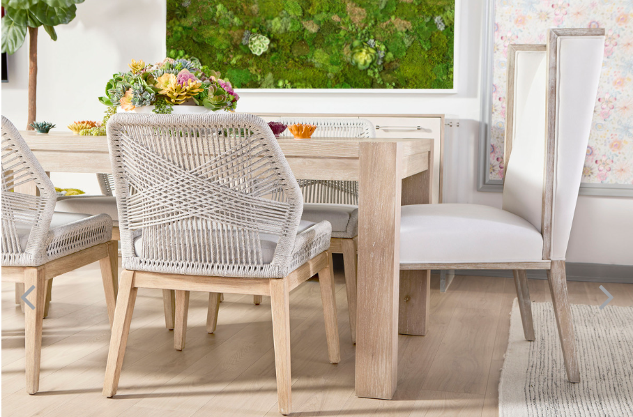 Corner of sand colored dining table with high back and weaved back chairs.