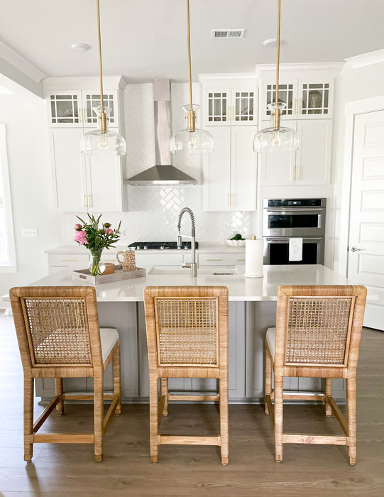 Gray and white kitchen island with three wicker stools.