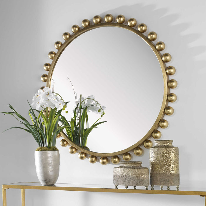 Round mirror on wall with gold ball accents.