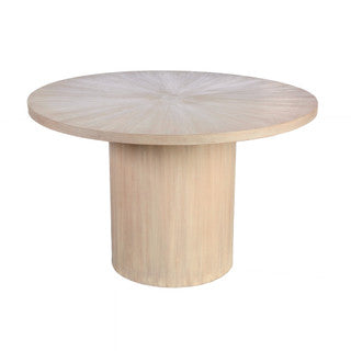 Angled down view of round light brown dining table.