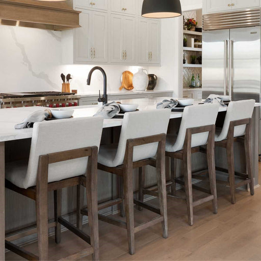 Diagonal shot of white and brown kitchen island and rounded stools.