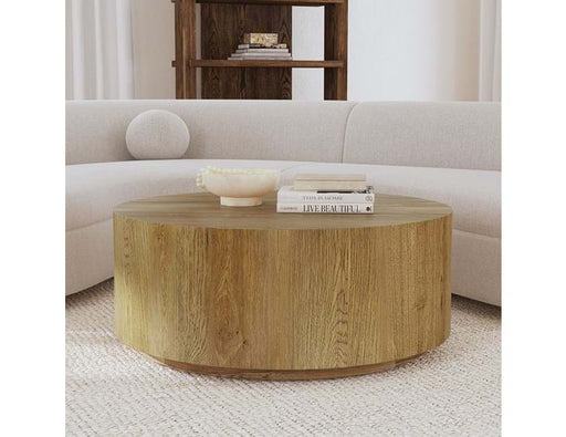 Round brown wood coffee table with books and bowl.