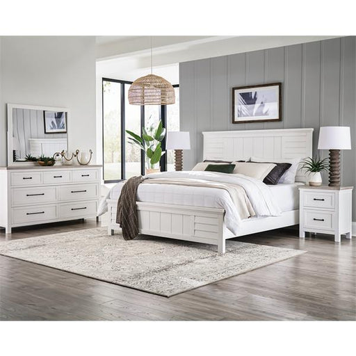 Diagonal coastal bedroom with rattan light and white dressers with black drawer pulls.
