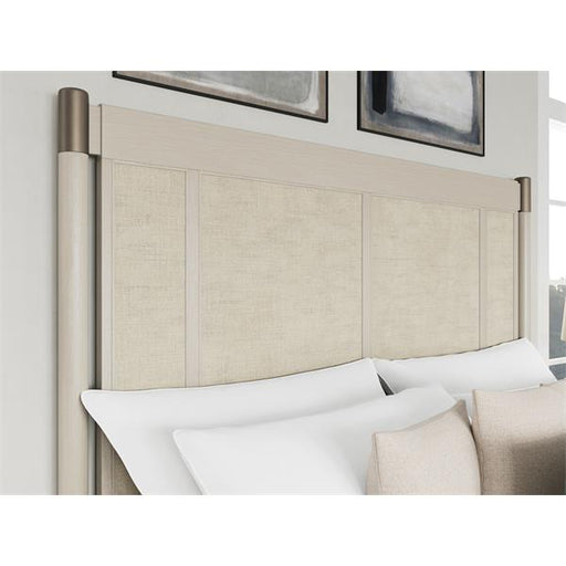Corner of cream colored headboard with silver corner accents.