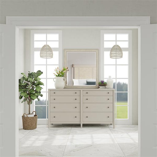 Look inside bedroom door with white eight drawer dresser with mirror.