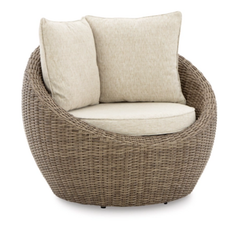 Angled view of round wicker chair with cream cushion.