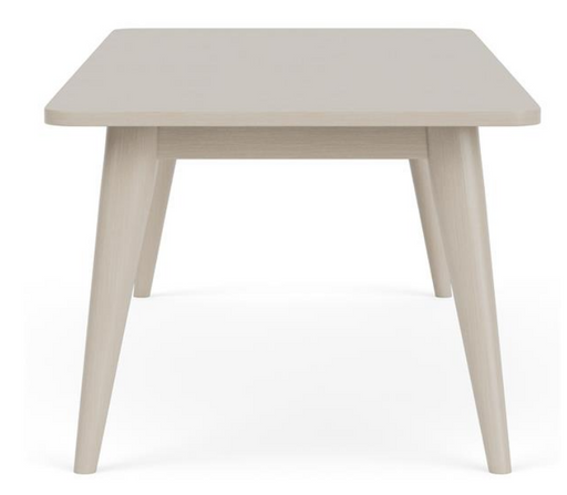 Side view of cream colored dining table with legs angling outward.