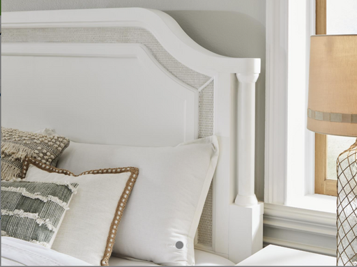 Corner of white carved headboard next to window.