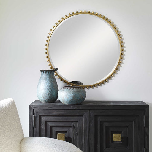 Image of brown accent table in front of gold ball accent mirror.