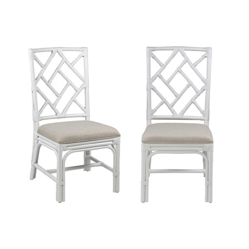 Two white wood dining chairs with cross back and cream cushions.