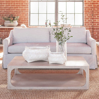 Cream colored loveseat and coffee table with flowers.