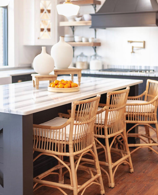 White kitchen island with gray detail and tan wicker barstools.