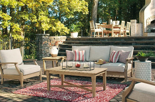 Backyard patio area with tan and cream furniture and red rug.