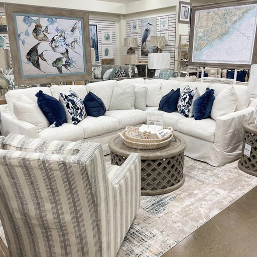 Angled view of cream living room arrangement with blue pillows and round gray table.